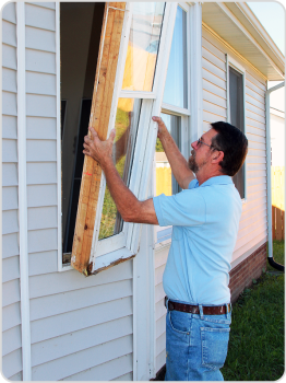 man replacing a window on a house